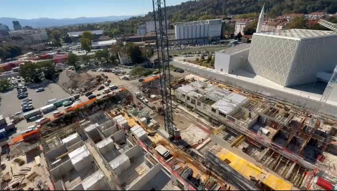 Zračni pregled urbanega stanovanjskega razvoja z modularnim opažem in stolpičnim žerjavom.